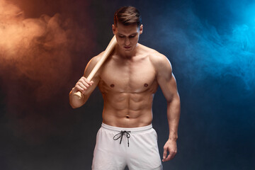 Fototapeta na wymiar Waist up portrait view of muscle man posing in studio with baseball bat