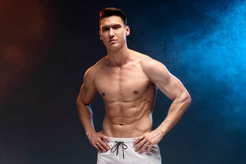 Fototapeta na wymiar Athlete man with beautiful torso isolated on black background with coloured fume