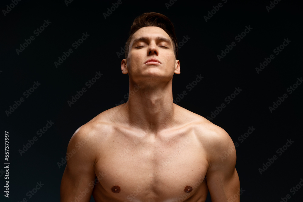 Wall mural image of handsome concentrated man standing naked isolated over black wall background