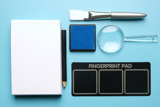 A flatlay picture of copyspace notepad, pencil, inkpad, magnifying glass and brush. Crime scene investigation concept