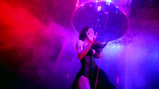fashion model woman swimming in pool with purple lights, underwater slow motion shot