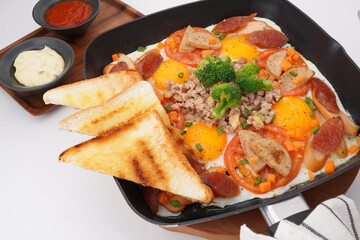 Fast food breakfast, fried eggs in pan and vegetables