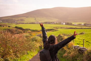 Girl with open arms travels alone through Ireland.