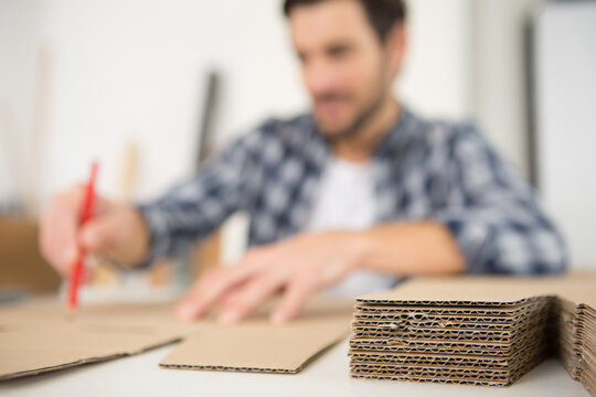 male worker drawing a design on cardboard