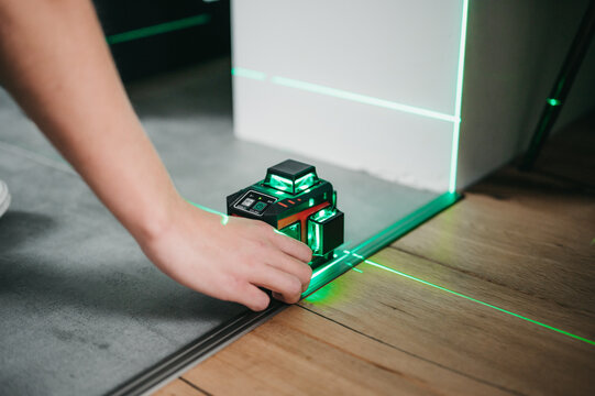 Builder and handyman using laser leveler to measure and draw lines and check interior