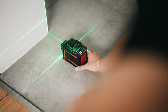 Builder and handyman using laser leveler to measure and draw lines and check interior