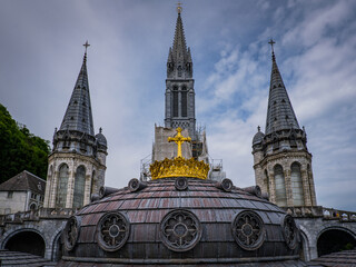 Fototapeta na wymiar The steeples and roof with golden cross of the neobyzantine Notre Dame de Lourdes Basilica in the South of France
