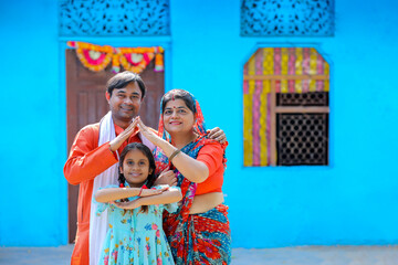 Fototapeta na wymiar Happy Indian farmer with wife and daughter making home shape with hand. dream home concept.