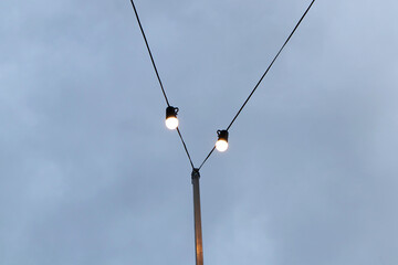 Light bulb night lamp lighting for safety. Fluorescent spiral bulb LED bulb and incandescent lamp on wires are enable to be turned on at the party. with sky and clouds in background during nighttime.