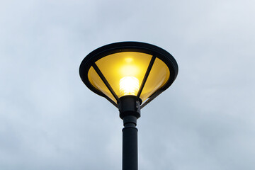 Light bulb night lamp lighting for safety. vintage street lamp post lantern lanterns at the park or enable to be turned on at the party. with sky and clouds in background during nighttime.