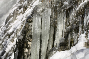 Fototapeta na wymiar Icicles on the slope of the rock.