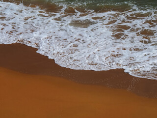 Aerial view of surf sea meets red sandy beach