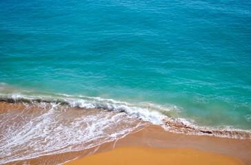 Aerial view of surf in turquoise sea meets red sandy beach