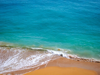 Obraz premium Aerial view of surf in turquoise sea meets red sandy beach
