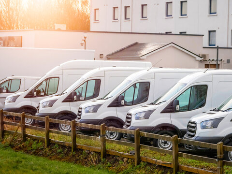 Row of white commercial vans in a dealership for sale or rent. Used and new busses. Transport industry.