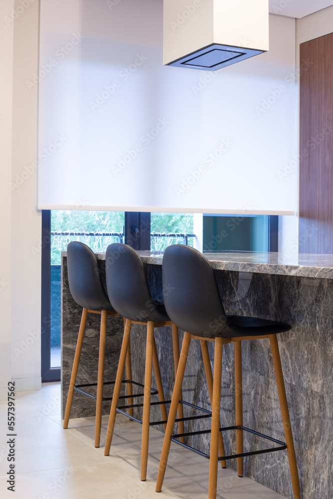 Aufkleber Roller blind large size on the window in the interior. Motorized roller shade white color in the kitchen. Bar counter with built-in hob and hood above it are near the window. Smart home concept. 