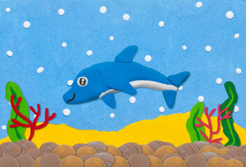 Obraz na płótnie Canvas blue dolphine made from plasticine on under water background