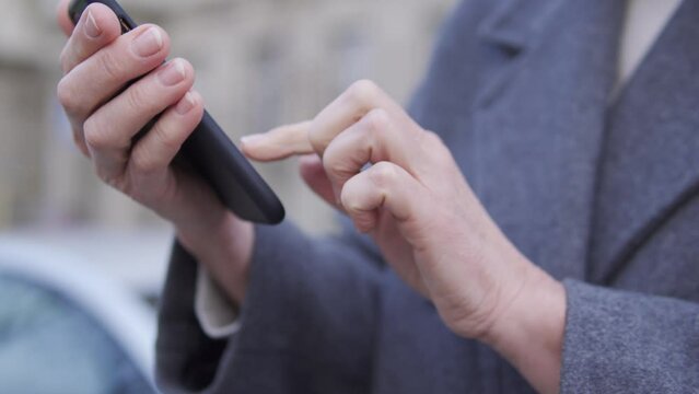 Woman dialing number on smartphone, calling the taxi, close-up female hands