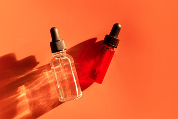 Face serum, oil, gel on beige background in the sunlight. Dropper bottles for cosmetics. Pipette...