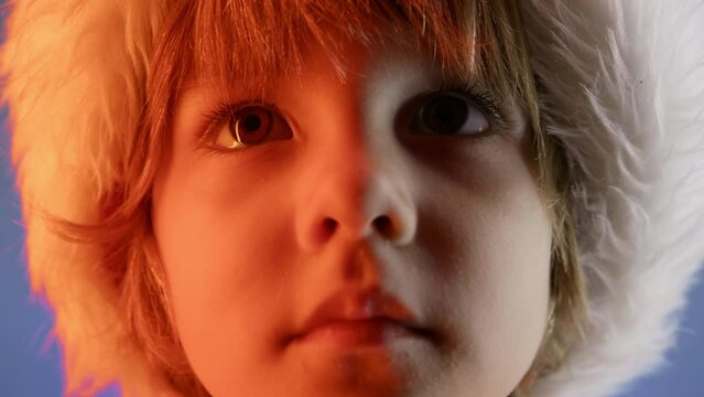Portrait of adorable boy in Santa Claus hat on blue studio background. Christmas celebration. Happy childhood, kid, lovely son