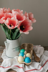 Easter symbols colored eggs and Panettone. Pink tulips in a metal jug. Easter holidays in Ukrainian style