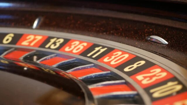 Ball on wooden french roulette table in casino. Wheel spinning, turning or rotating. Odd and even numbers, black, red and zero sectors. Bets in game of chance. Money playing, gambling or risky betting