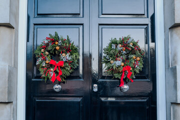 Green, red and white Christmas wreaths on a front door of an English house in London, UK.