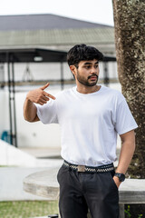 A young handsome bearded man wearing a blank white shirt doing a pose outdoor