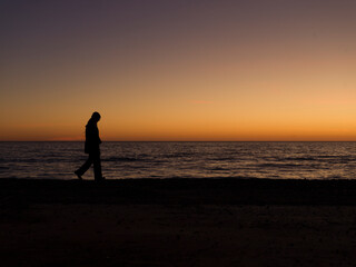 person walking on the beach at sunset