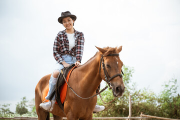 beautiful asian cowboy girl standing beside horse on outdoor background