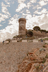 El famoso Castillo Vila Vella y sus murallas de Tossa del Mar bajo un cielo azul con las nubes en movimiento en un día de Noviembre.