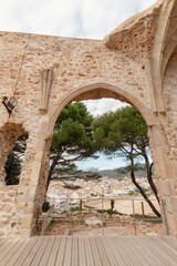 Fototapeta na wymiar Ventanas de piedra de la antigua Parroquia de San Vicente de Tossa de Mar con vistas a las casas del pueblo y sus tranquilas playas.
