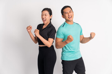excited asian woman and man standing back to back shouting with hands clenched up on isolated background