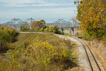The Natchez–Vidalia Bridge over the Mississippi River seen through the trees and old railroad...