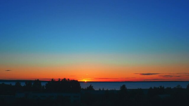 orange-red dawn and sunrise in summer. Sunrise and the rise of the sun disk above the horizon. Rising sun. Clouds give way to clear blue skies. Time lapse 4k. Lifting sun disk. Glare of the sun