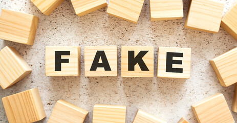 The word FAKE consists of wooden cubes with letters, top view on a light background.