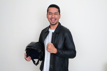 Asian man wearing black leather jacket holding motorcycle helmet with excited expression - Powered by Adobe