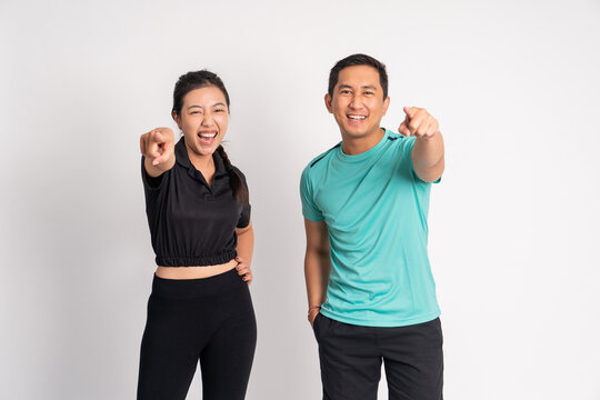 asian woman and man laughing with fingers pointing forward on isolated background