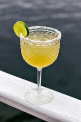 Tequila and beer cocktail (cozumel), garnished with salt and a slice of lemon, resting on a white board, with the sea in the background