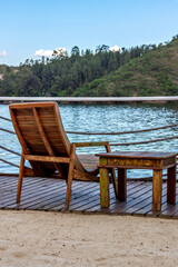 An empty wooden chair and small table facing the view with beautiful lake and mountains. Vertical