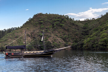 Boat (schooner) sailing on a quiet lake with mountains in the background on a blue sky day