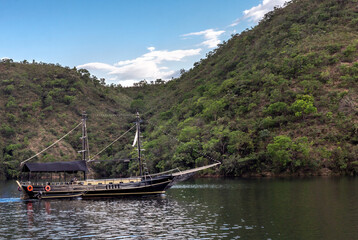 Boat (schooner) sailing on a quiet lake with mountains in the background on a blue sky day