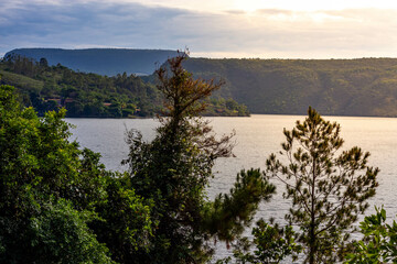 Beautiful landscape of peaceful lake at sunrise with trees and vegetation in the foreground