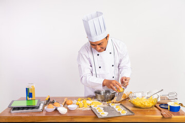male chef using grater while grating cheese onto cake on tray on isolated background