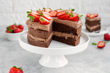 Naked chocolate cake with cream and fresh strawberries on top. Rustic style. Selective focus. Copy space.