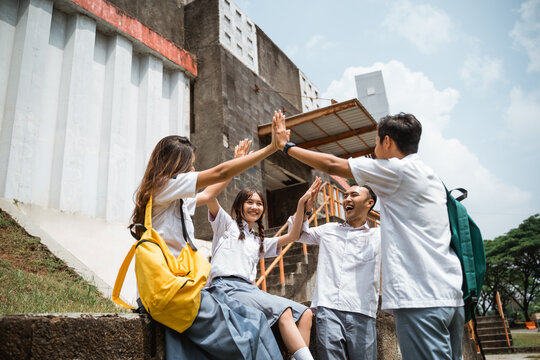 Asian high school students holding hands while forming a union