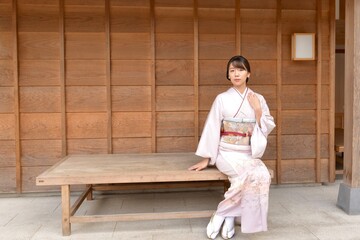 椅子に座ってポーズをとる若く美しい着物姿の女性