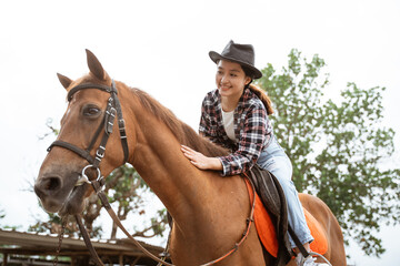 Obraz premium beautiful cowboy girl riding horse while stroking on outdoor background
