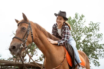 Foto op Canvas beautiful cowboy girl riding horse while stroking on outdoor background © Odua Images