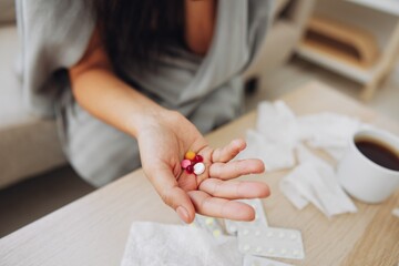 A woman with a cold with pills is treated at home chooses which drugs to take and self-medicates,...